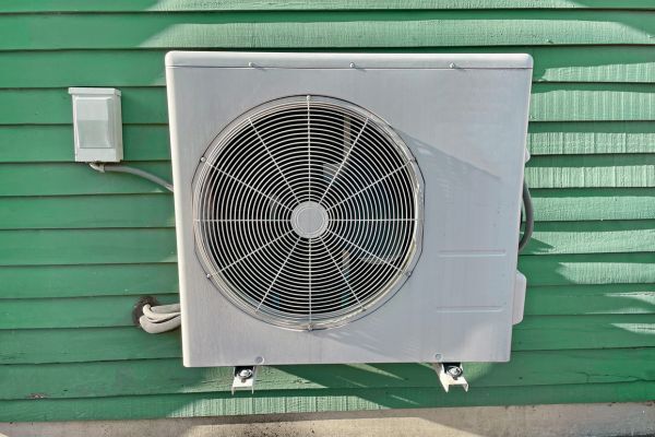 An outdoor unit of a split system heat pump against a green background