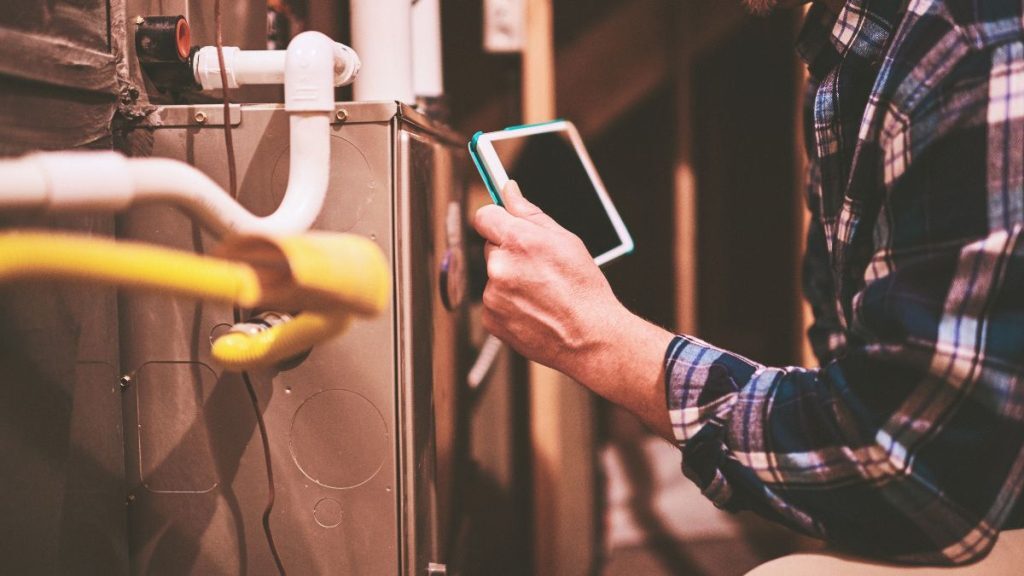 a man holding a tablet in front of a furnace