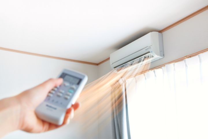 Man Turning On Air Conditioner Using Remote
